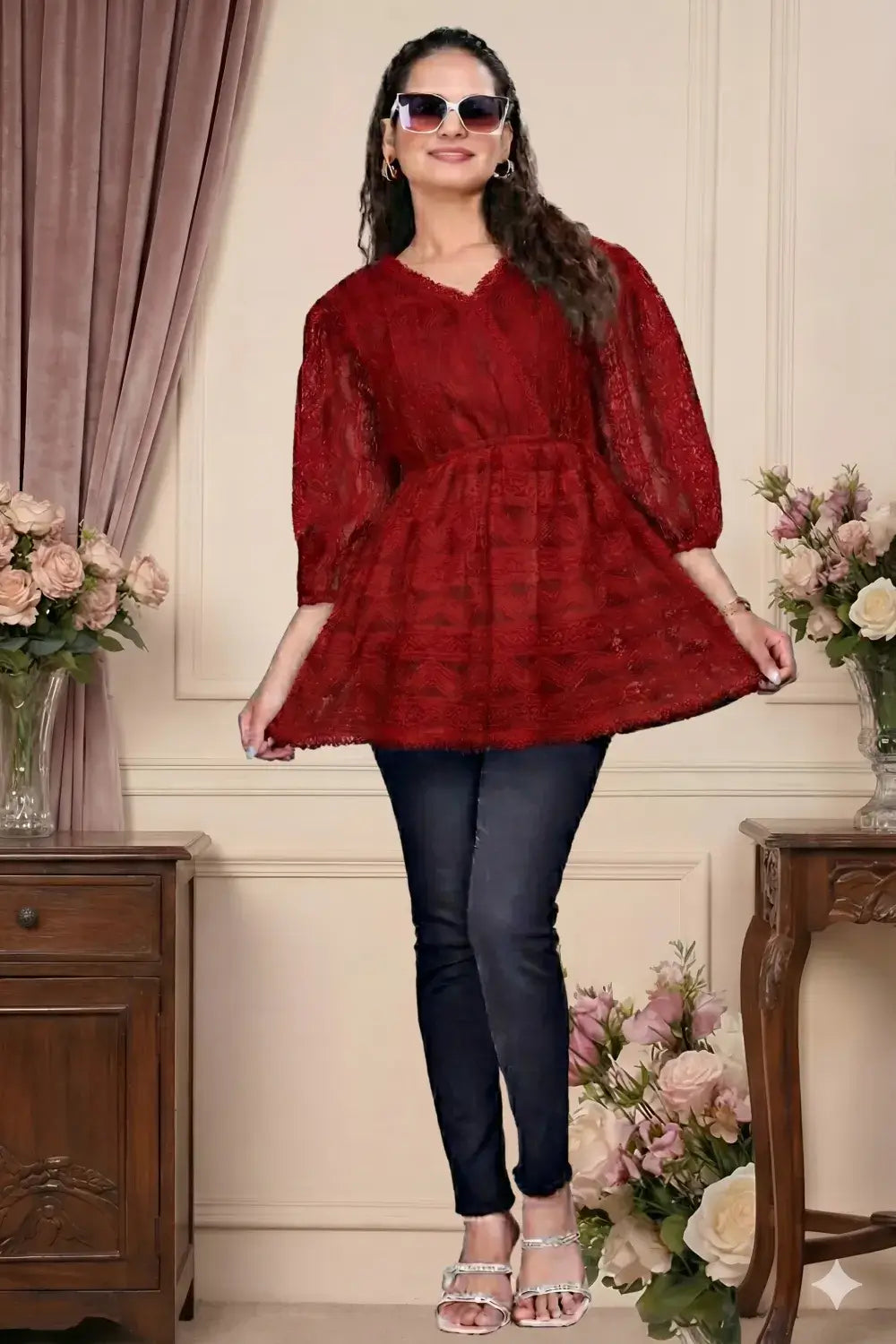 Woman wearing a red dress and black pants in an elegant room with flowers and furniture.