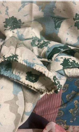 Fabric with a nature-themed pattern featuring trees and blue sky.