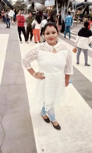 Woman in a white outfit standing on a sidewalk with people in the background