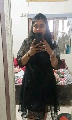 Person wearing a black dress taking a mirror selfie.