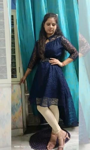 Woman in a blue dress standing in front of a teal curtain