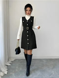 Woman wearing a black dress with white buttons, white turtleneck, and black knee-high boots against a plain background.