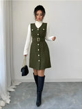 Woman wearing a green dress with a belt and black knee-high boots in an indoor setting.