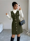 Woman taking a mirror selfie wearing a green dress with white buttons, white turtleneck, and black knee-high boots.