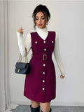 Woman wearing a burgundy dress with white buttons against a plain background