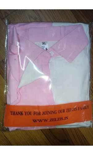 Pink and white shirt in clear packaging with an orange banner at the bottom on a wooden surface
